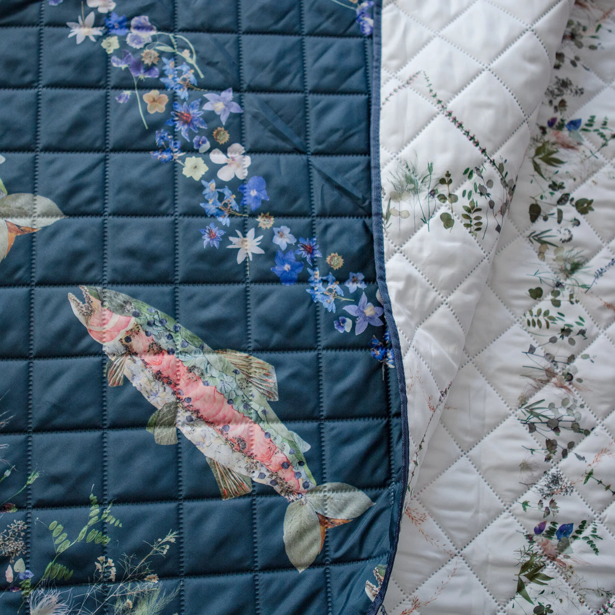 Two sides of an outdoor themed picnic blanket with floral and fish designs on a turquoise and white background.