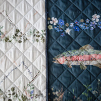 Floral and fish designs on a double-sided outdoor blanket with an outdoorsman theme