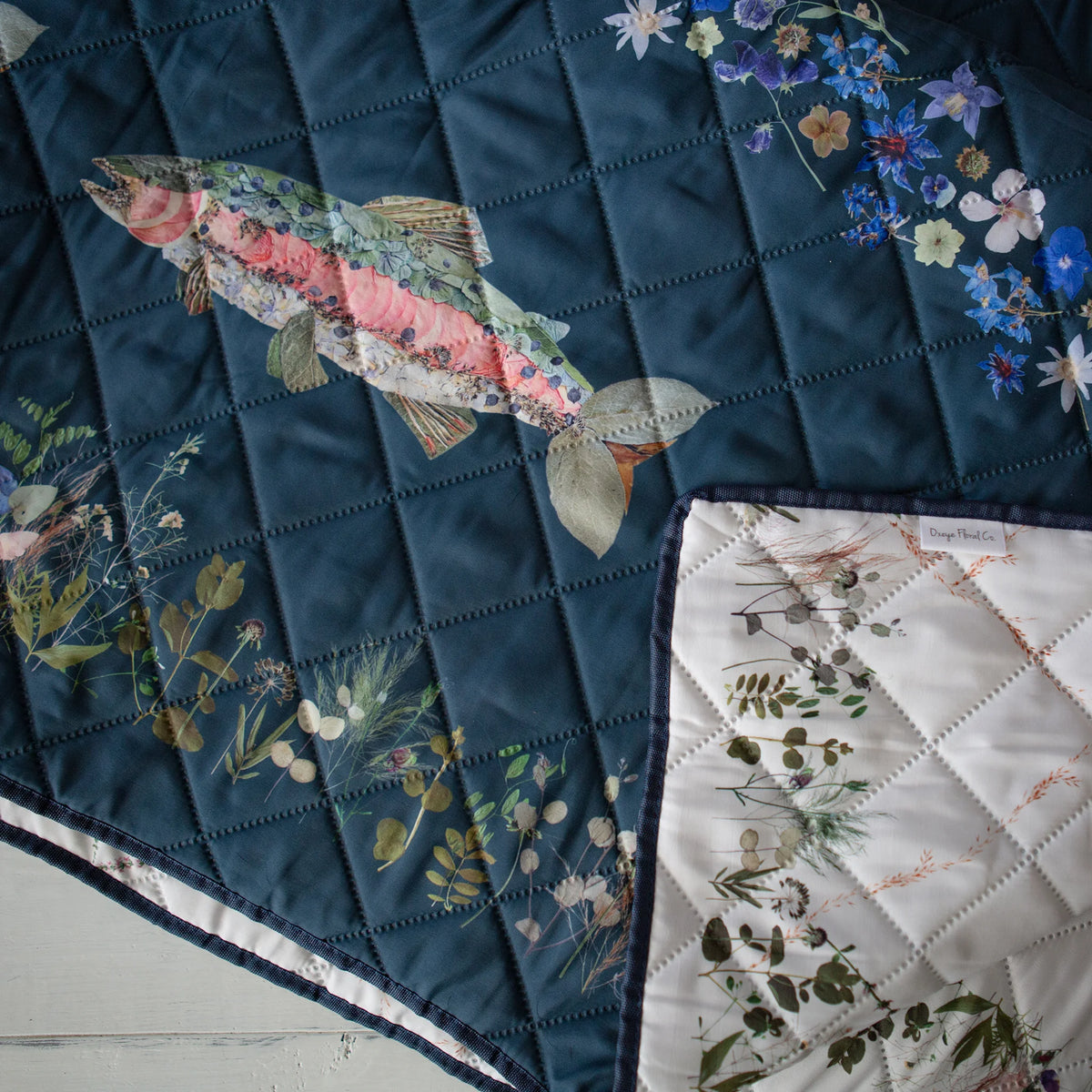 Double-sided picnic blanket with floral trout design on a turquoise background