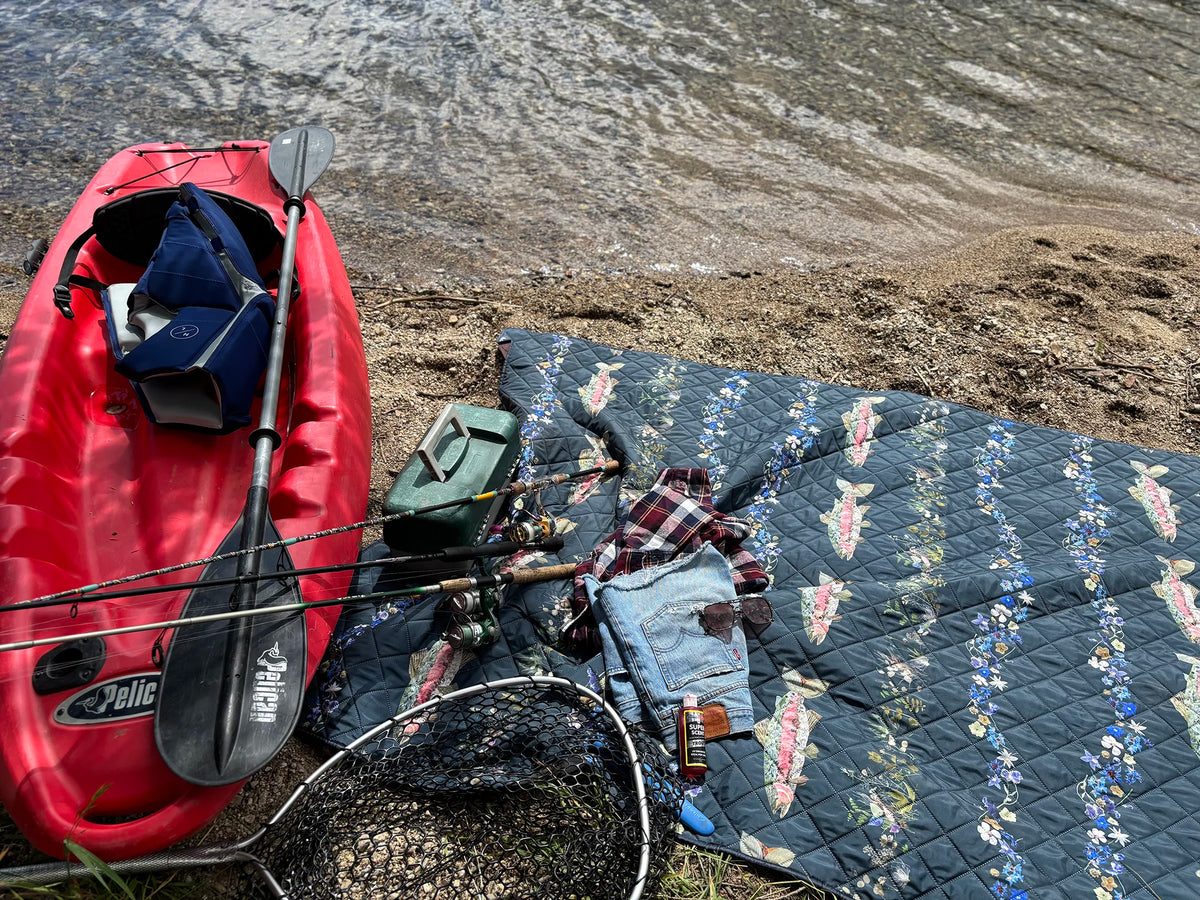 Kayak with fishing gear and an outdoor blanket on a sandy beach