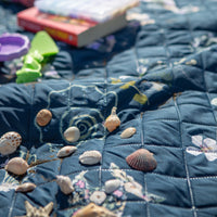 Coastal themed outdoor picnic blanket with seashells and sand