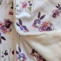 Bunny shapes made from pressed flowers on a soft fabric with colorful flowers on a white background