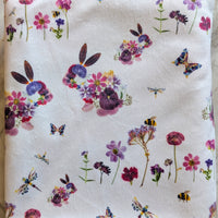 Pressed floral bunny and insect pattern on a white baby blanket
