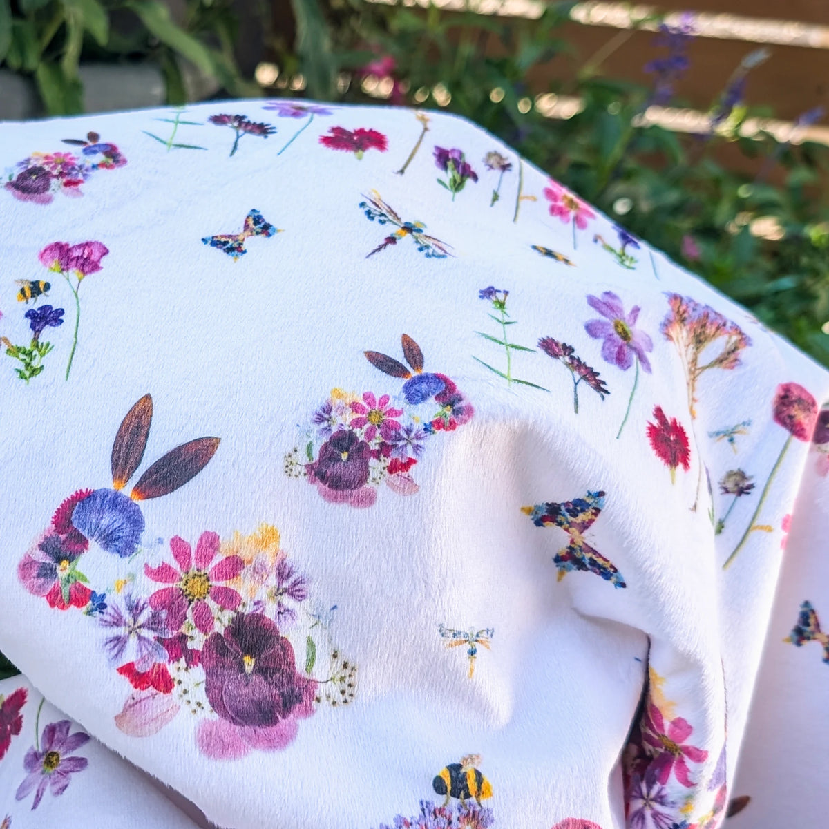 Floral rabbit and insect patterned minky blanket with a white background