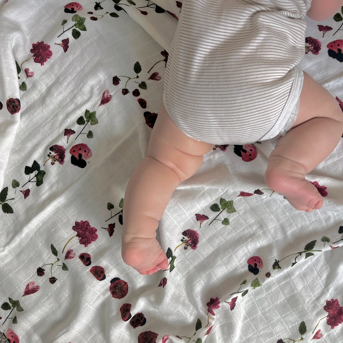 Pressed flower ladybug design on a cotton muslin swaddle