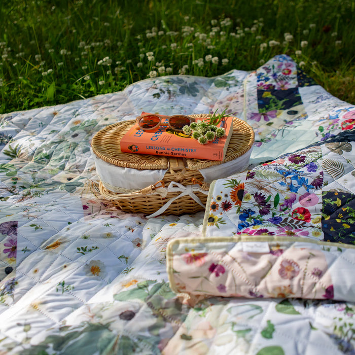 Floral Outdoor picnic blanket with a picnic basket and food on a grassy field