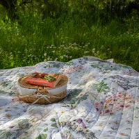 Verona Voyager Blanket used as a picnic blanket in a grassy clover field