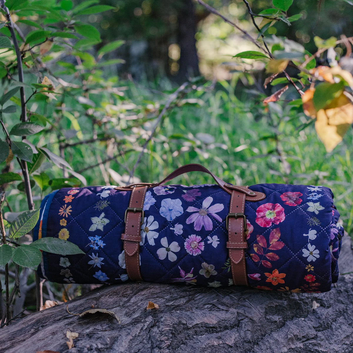 Floral-patterned rolled up blanket on a tree stump with a natural background