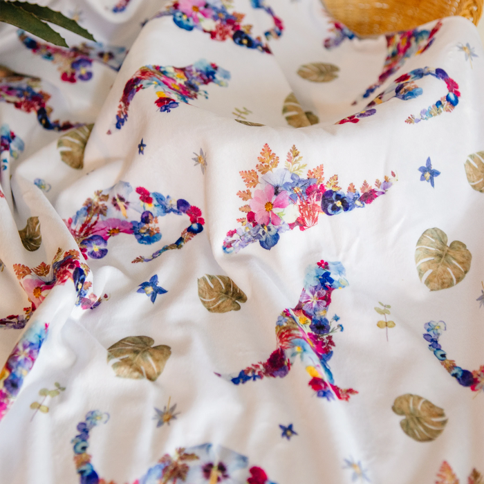 A close-up of a dinosaur-themed baby blanket with a pressed flower print.