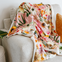 Pressed Flower Peaches and Sunshine blanket on a cream coloured couch