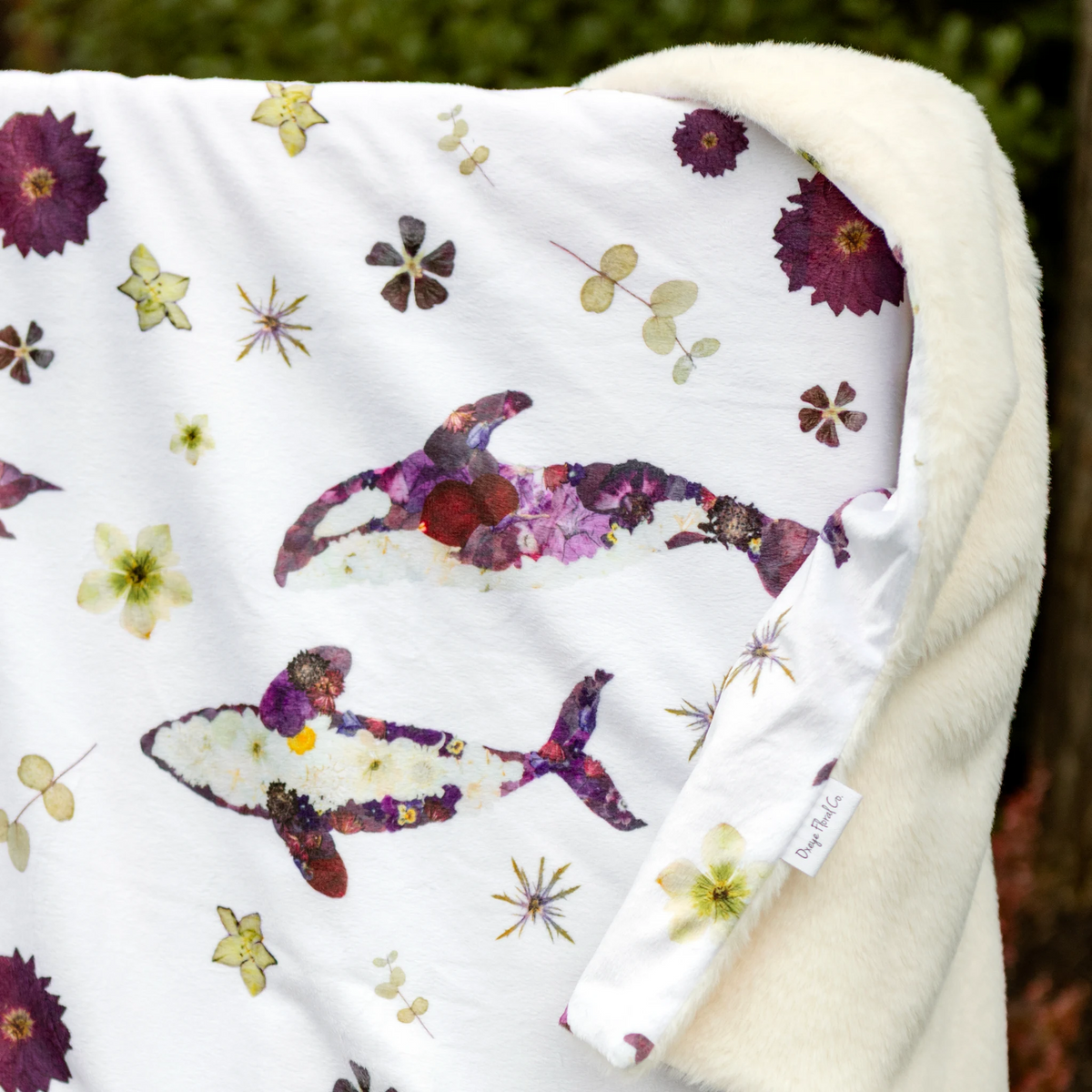 Closeup of a minky baby blanket with pressed flower design featuring orca whales