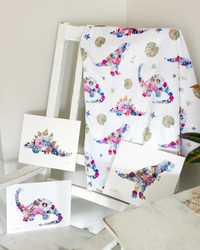 Pressed flower dinosaur baby blanket hanging on a chair with three matching dinosaur floral prints.