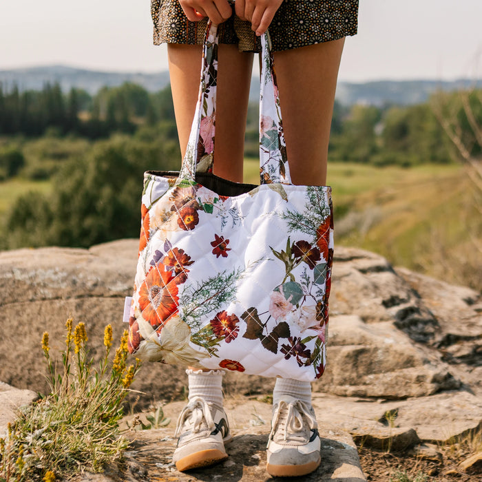 Girl holding Oxeye Floral Co Lily and Ember Tote on a rock in a field