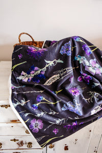Floral-patterned blanket on a wooden surface with a wicker basket in the background