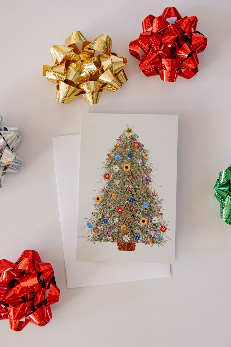 Decorative greeting card with a Christmas tree design surrounded by colorful bows on a white background