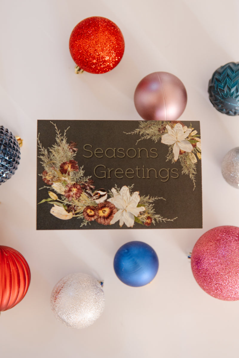 Seasons Greetings card with decorative ornaments on a light background