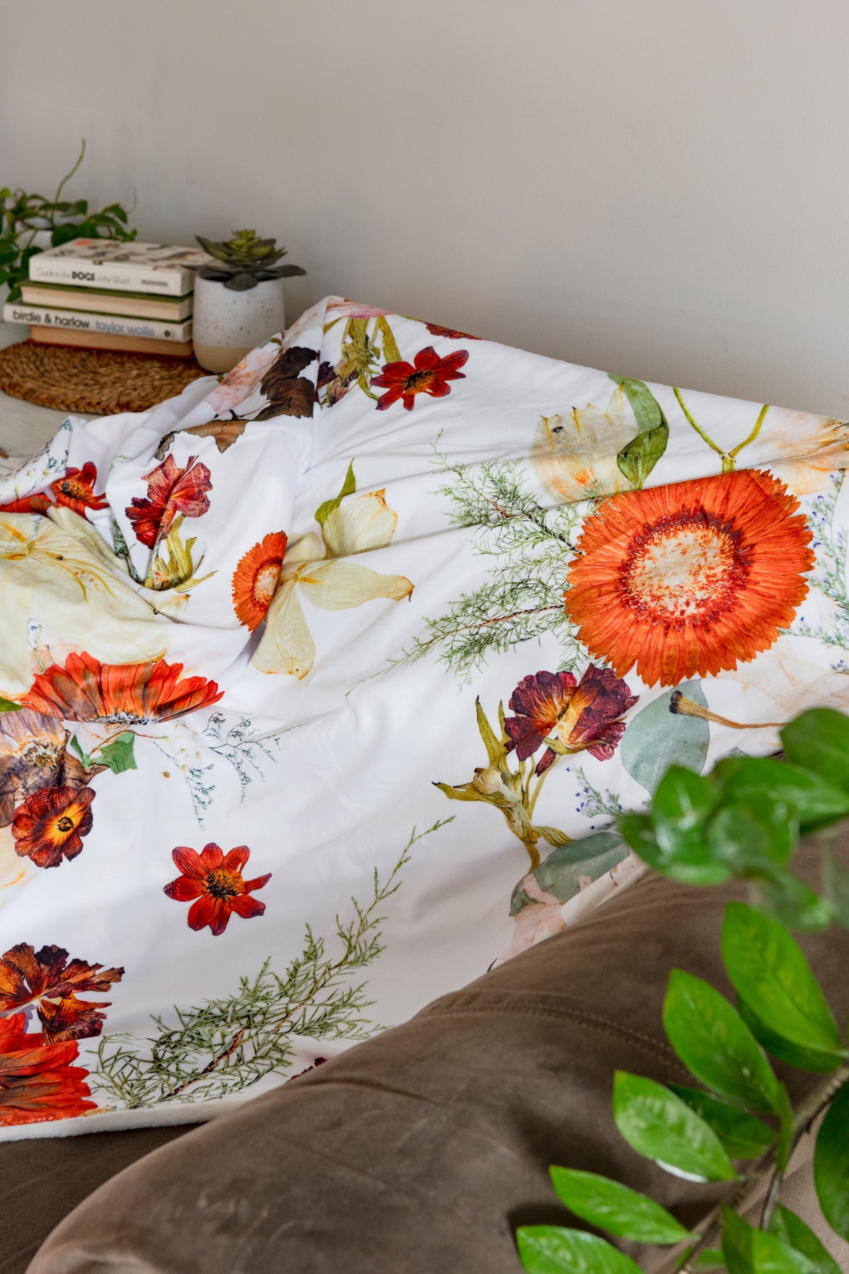 Floral-patterned throw blanket on a couch with a plant in the foreground