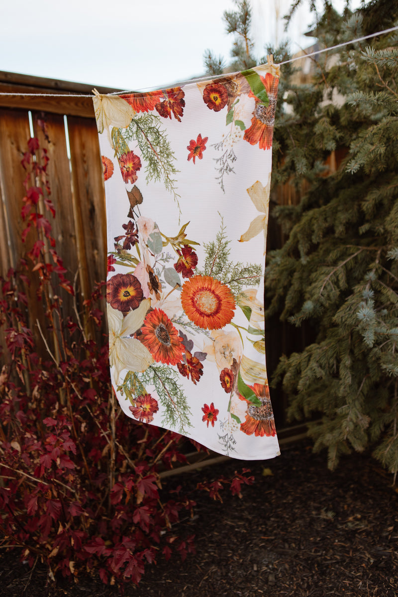 Floral-patterned towel hanging on a clothesline with trees in the background