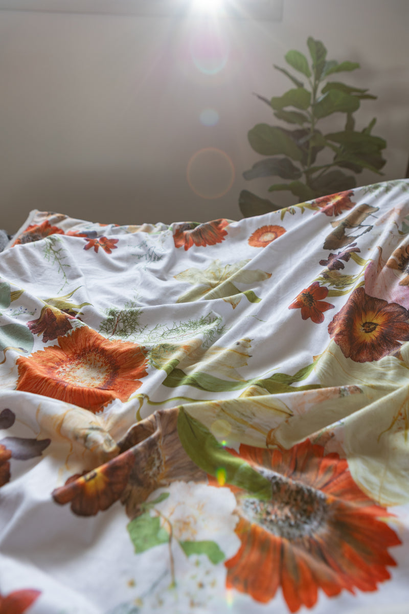 Floral patterned blanket with orange and green colors on a white background