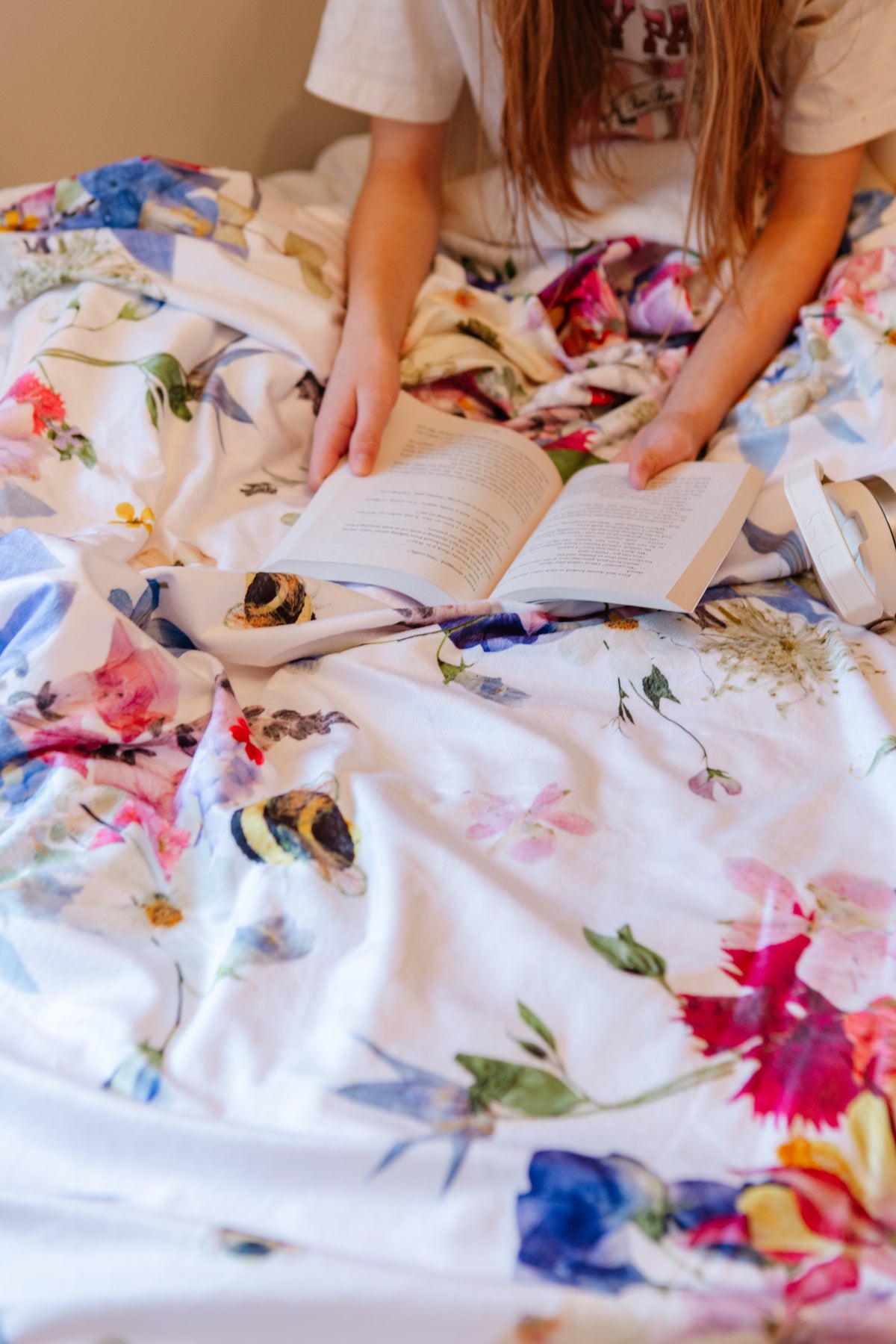 Person reading a book on a floral blanket
