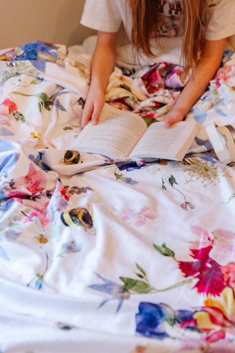 Person reading a book on a floral blanket