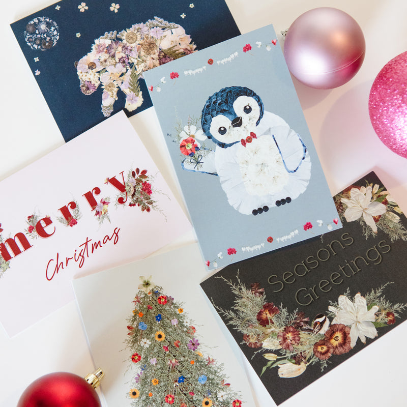 Collection of Christmas cards with penguin design and floral elements.