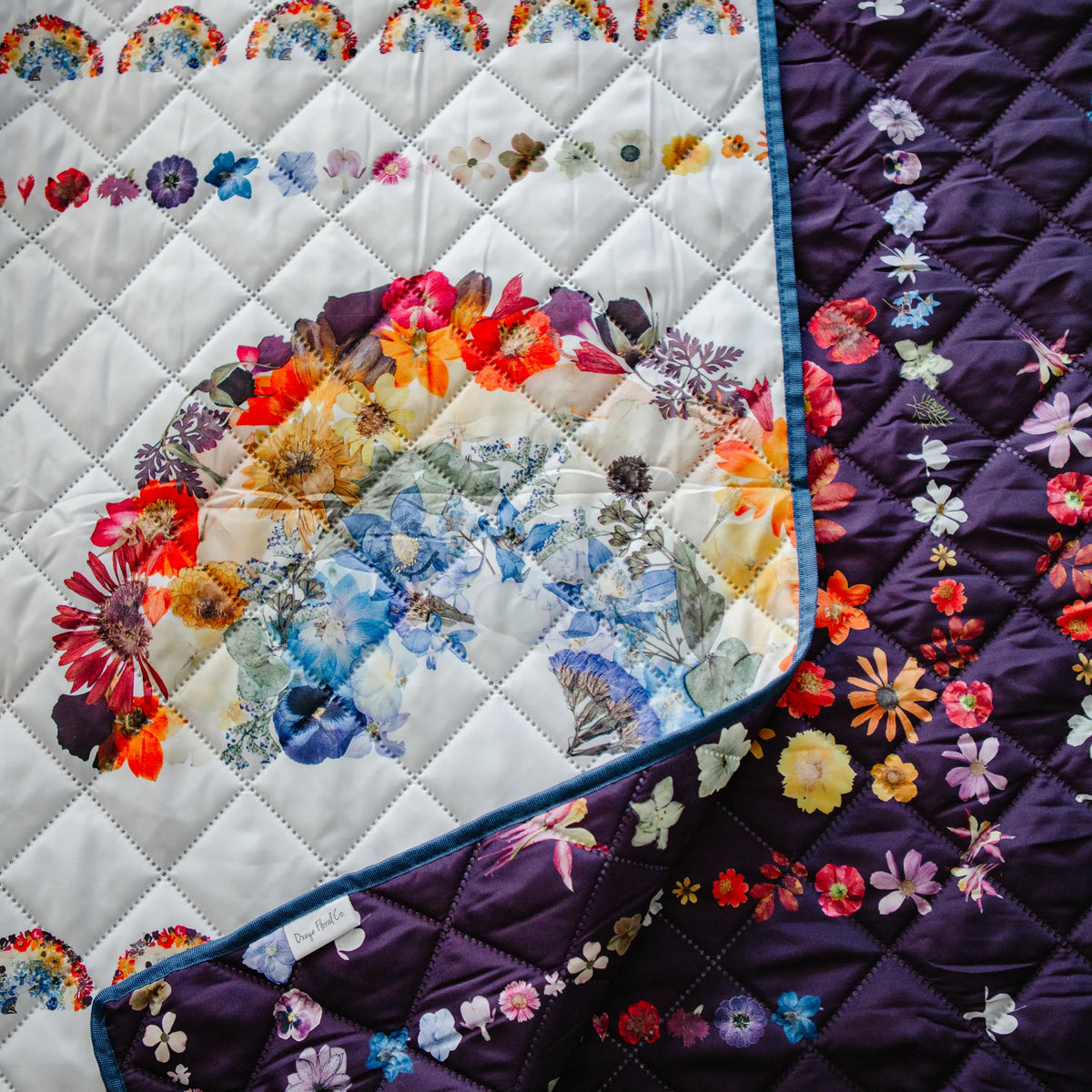 Picnic blanket with two floral rainbow themed sides shown