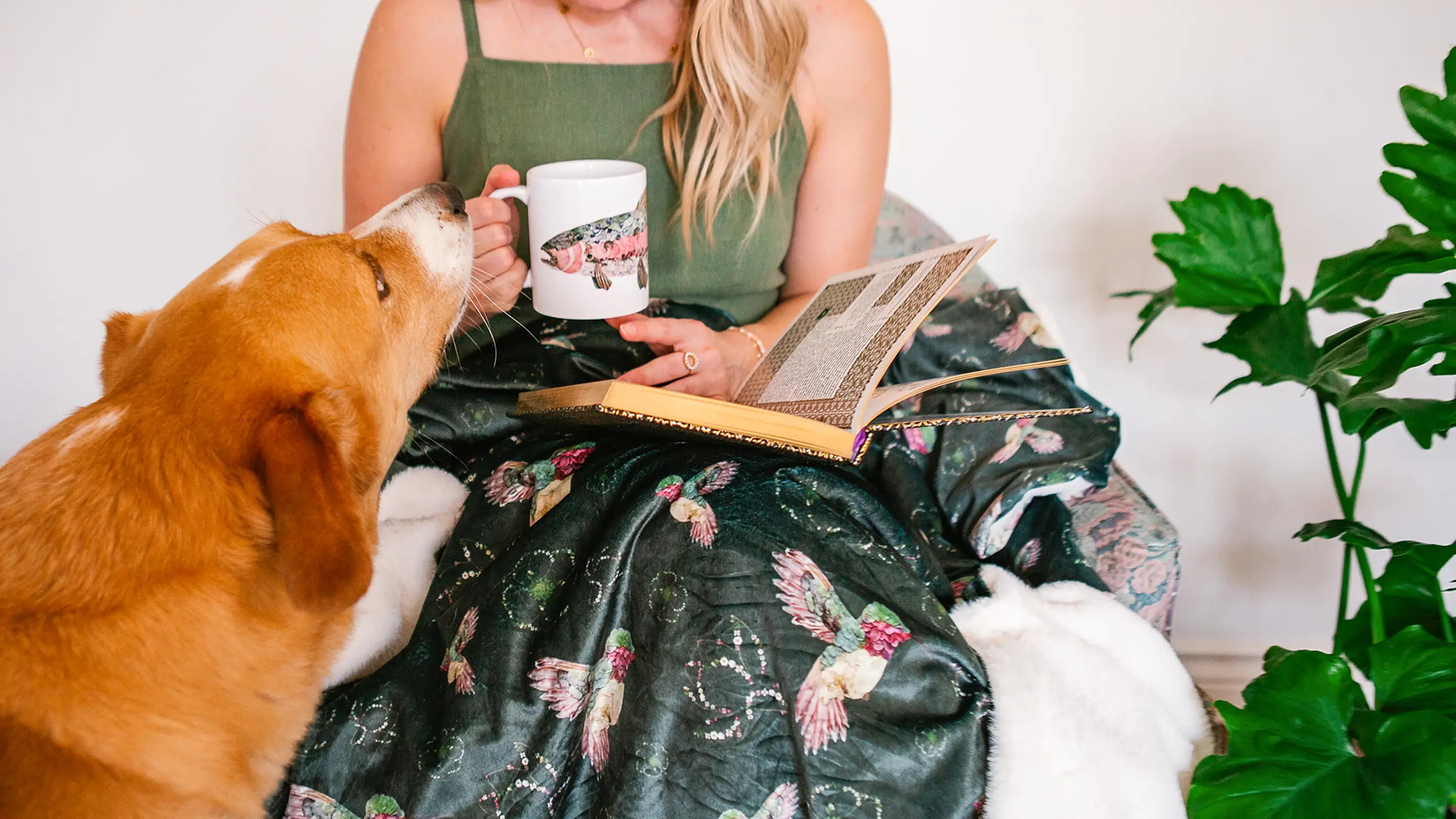 Woman holding a fish-themed mug with a floral hummingbird blanket