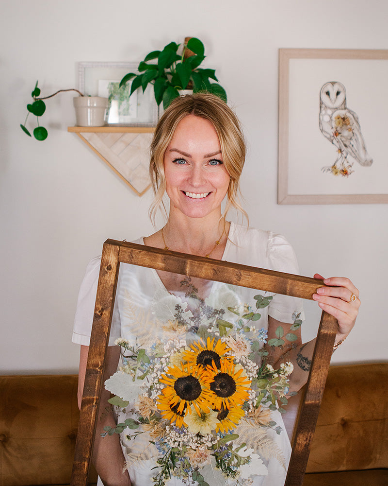 Ayla Graham holding framed pressed floral artwork