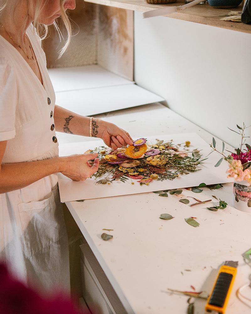 Ayla Graham arranging pressed flowers in studio