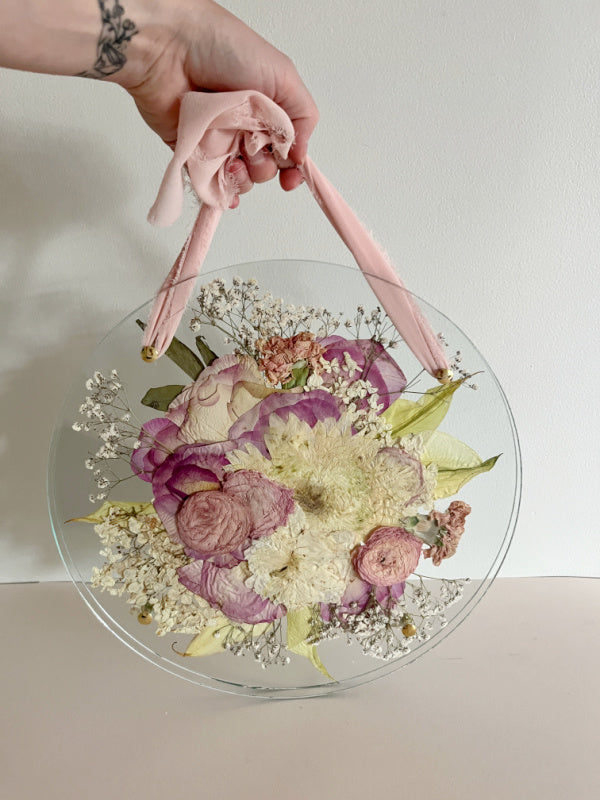 Pressed bouquet in an oval glass frame with pink ribbon by Oxeye Floral Co