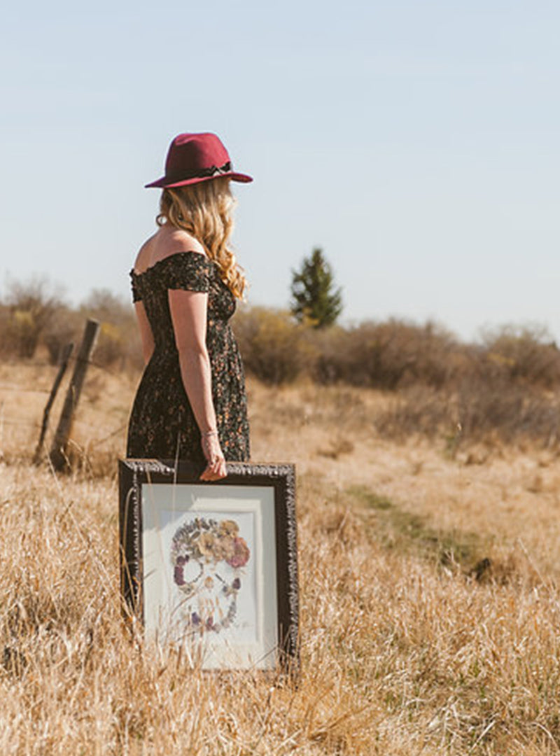 pressed flower artist holding an original art piece