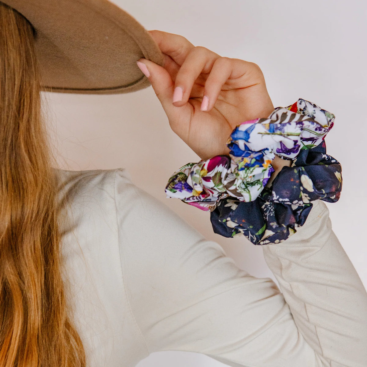 Person holding colorful scrunchies with a neutral background