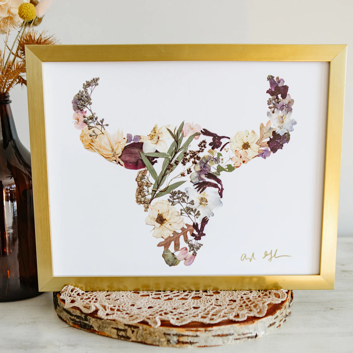Framed floral artwork with a gold frame on a white surface.