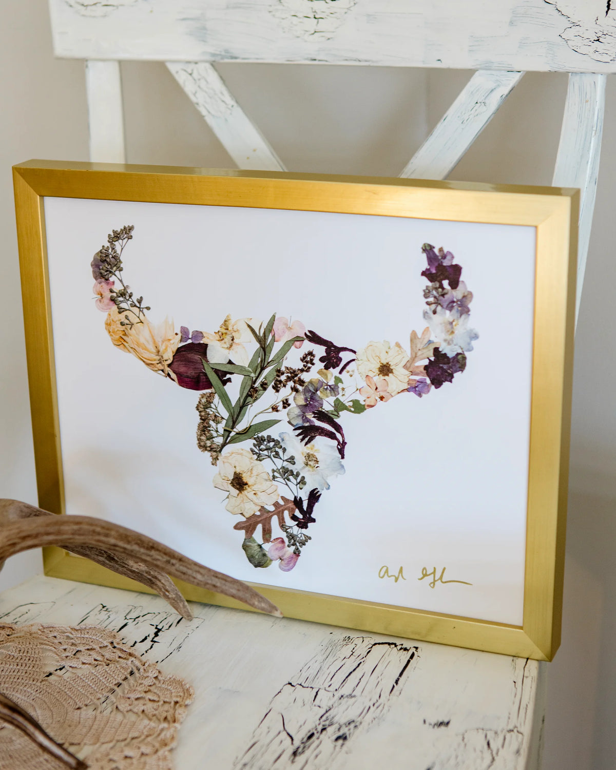Framed floral buffalo artwork with a gold frame on a textured surface