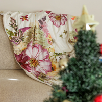 Cottage garden cottagecore throw blanket on a beige couch with a Christmas tree in the foreground