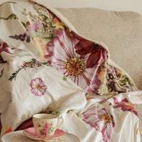 Feminine floral blanket on a beige couch with teacup in the foreground