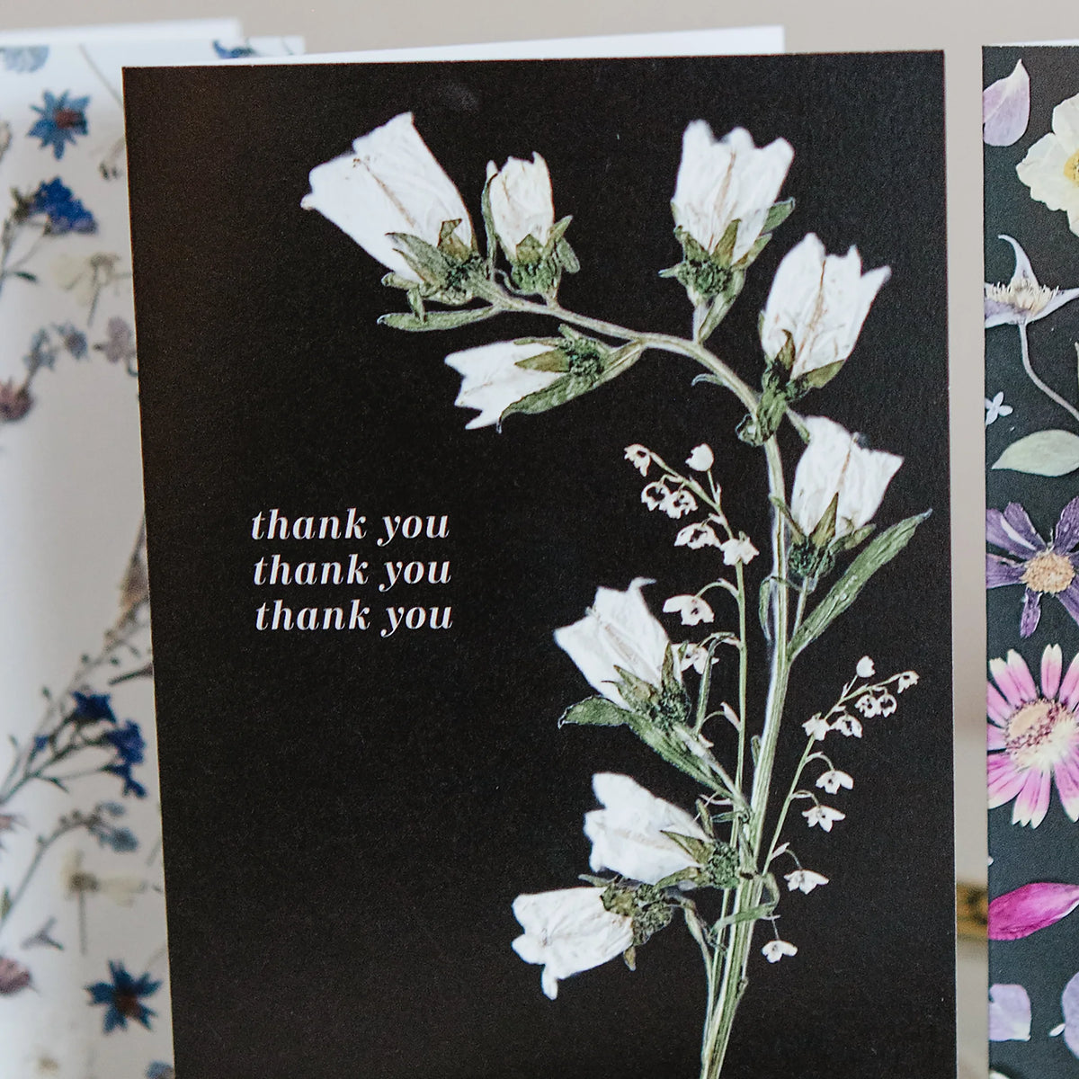 Floral card with white flowers and 'thank you' text on a black background