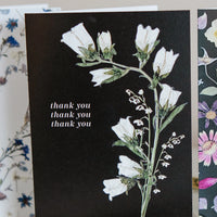 Floral card with white flowers and 'thank you' text on a black background