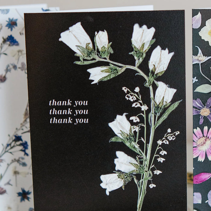 Floral card with white flowers and 'thank you' text on a black background