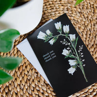Greeting card with floral design and 'thank you' text on a woven surface
