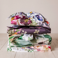 Four wrapped gifts stacked into a tower with floral faux silk gift wrap