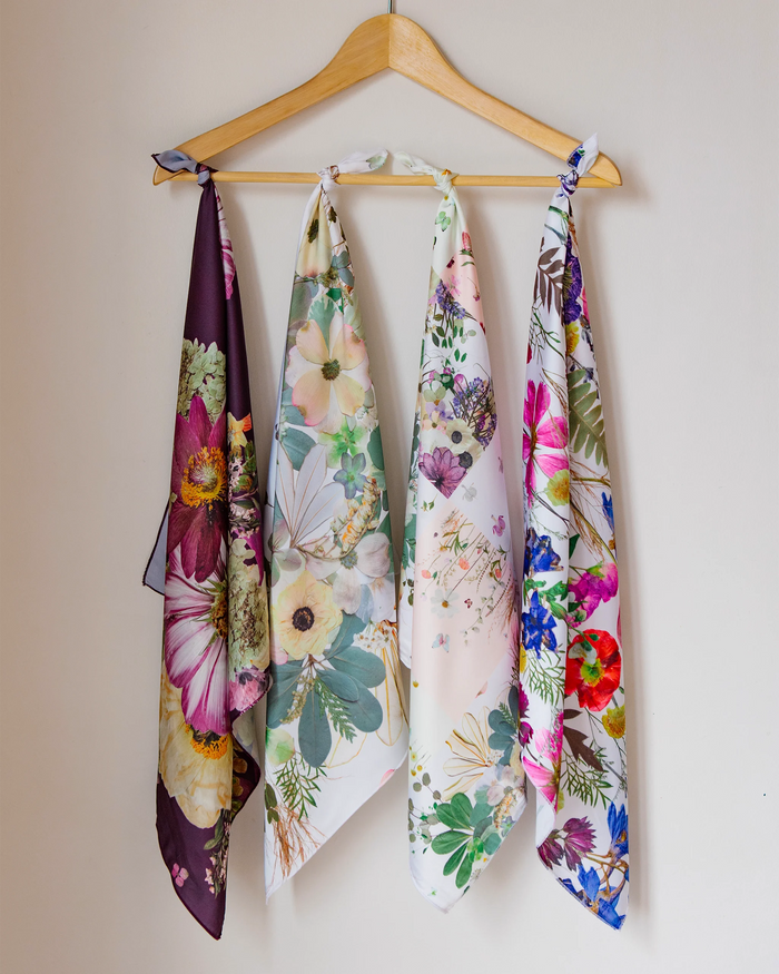 Four faux silk floral bandanas tied to a clothes hanger in a line.
