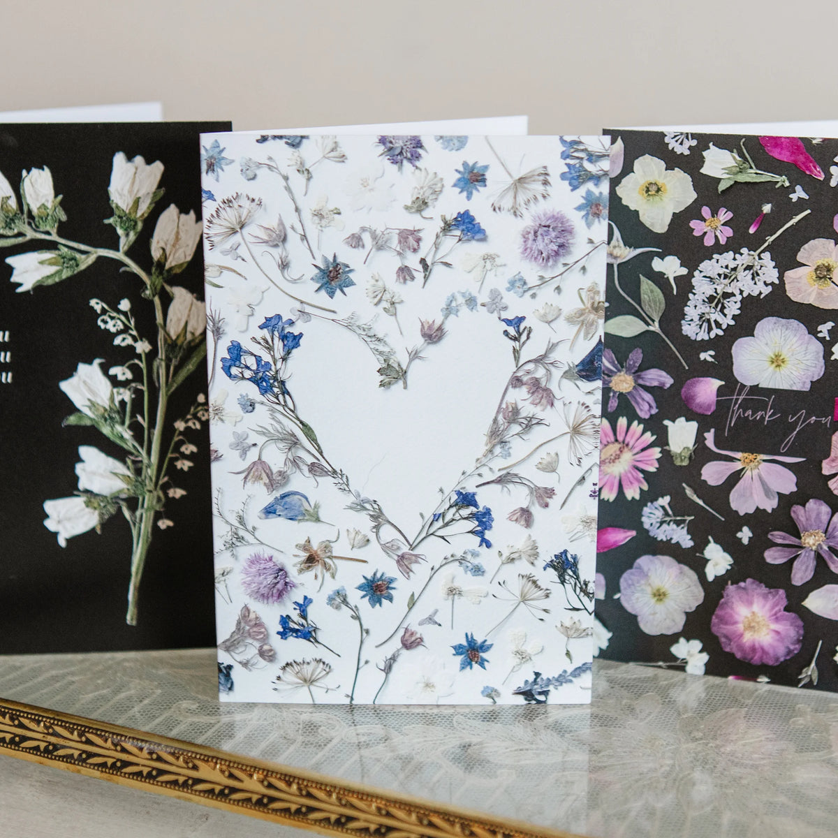 Three floral greeting cards on a neutral background