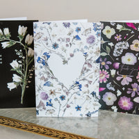 Three floral greeting cards on a neutral background