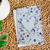 Floral greeting card with heart shape on a woven surface