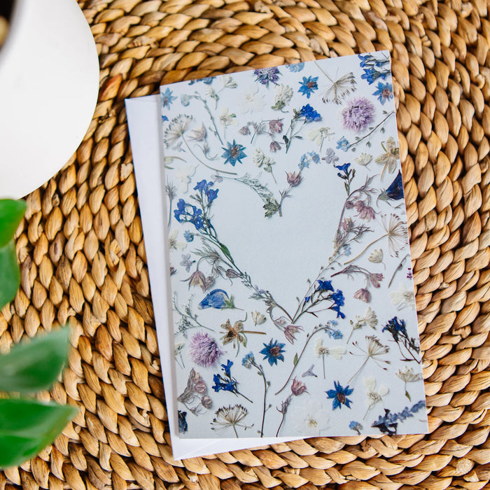 Floral greeting card with heart shape on a woven surface