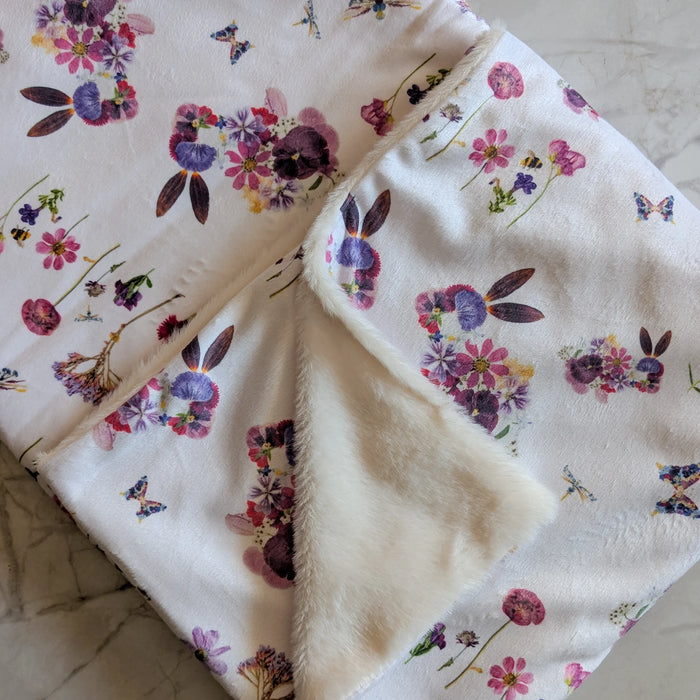 Bunny themed floral-patterned baby blanket with a soft texture on a neutral background