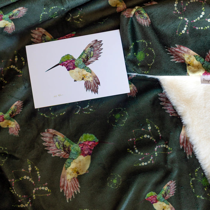 Card with a colorful floral hummingbird on a throw blanket with hummingbird patterns.