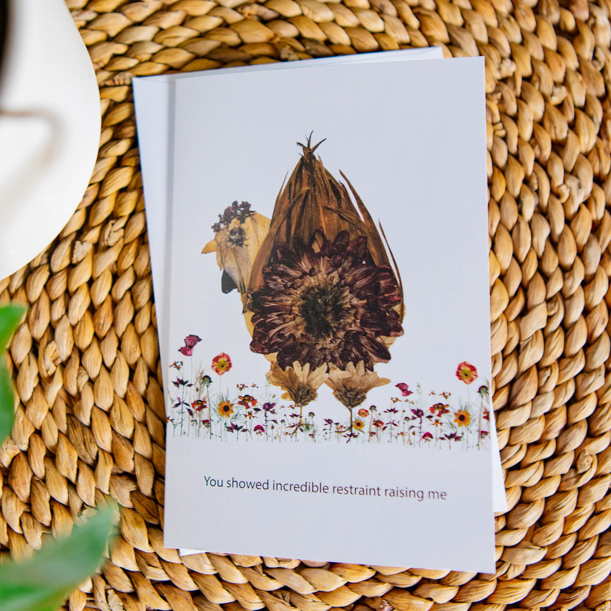 Greeting card with whimsical chicken design and text on a woven surface